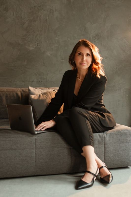 Grazi Amaral, fundadora da AMA MKT, sentada em um sofá trabalhando no notebook